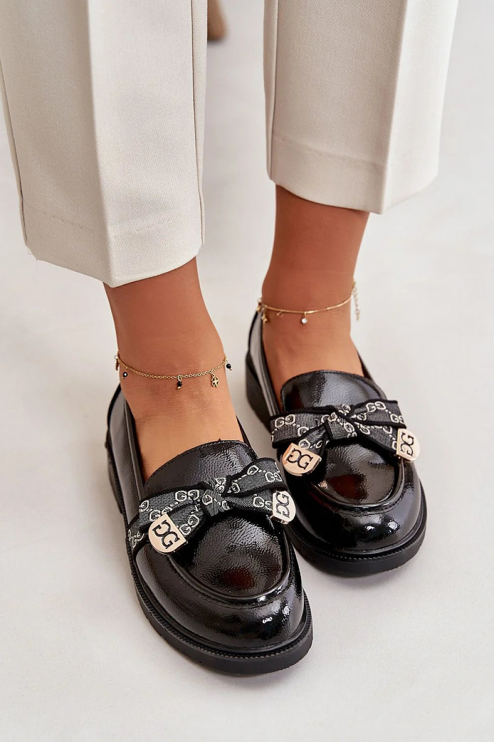 mocassins femme cuir verni noir silhouette basse bout arrondi semelle plateforme crantée talon plat noeud bandeau monogramme plaques métalliques dorées