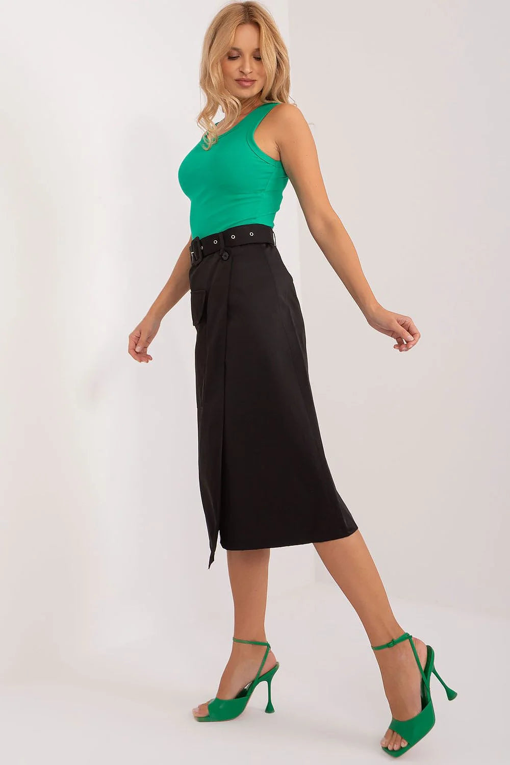 Ensemble élégant et moderne pour femme composé d'un haut vert vif, d'une jupe asymétrique noire et de sandales à talons vert
