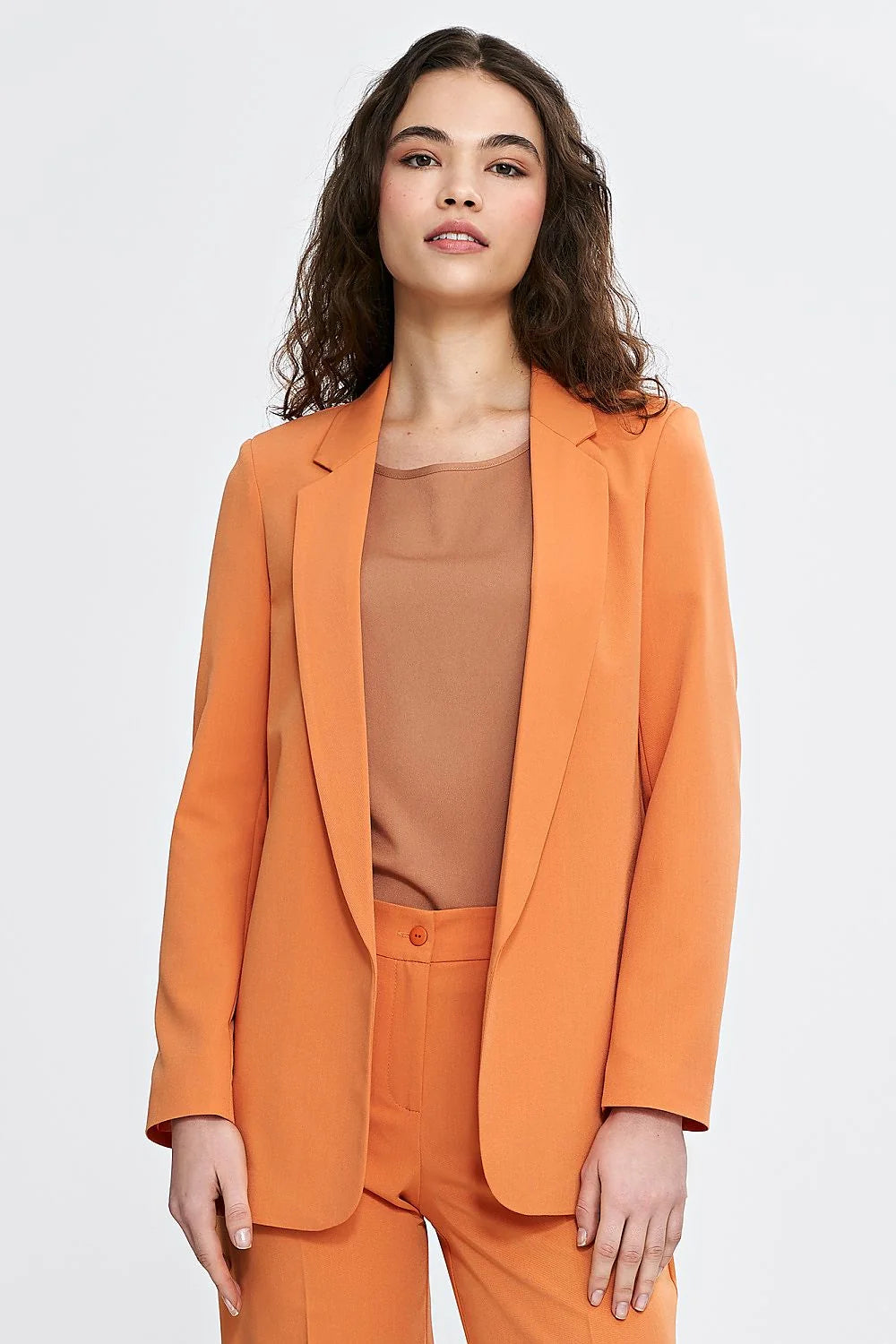 Tailleur élégant pour femme en orange vibrant, veste et pantalon, coupe classique, manches longues, épaules définies, occasion professionnelle