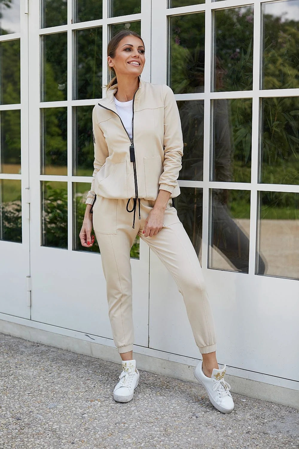 ensemble jogging femme veste zippée beige écru zip noir pantalon slim ajusté cordon serrage poches plaquées sneakers blanches florales dorées