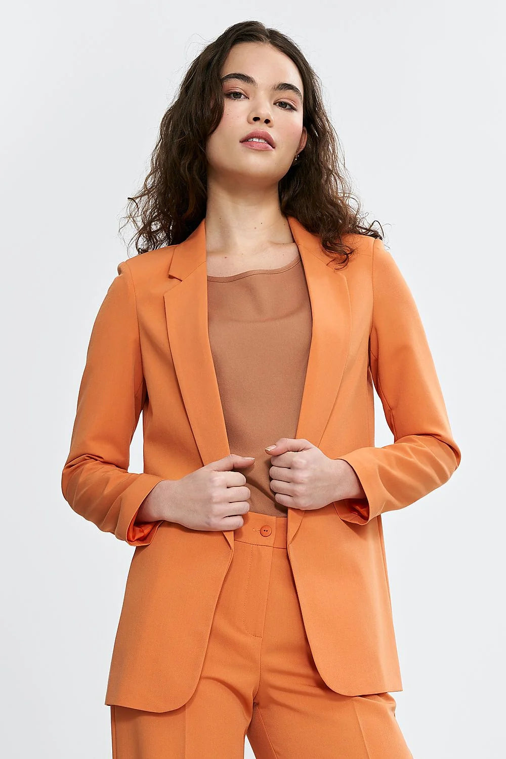 Tailleur élégant pour femme en orange vibrant, veste et pantalon, coupe classique, manches longues, épaules définies, occasion professionnelle