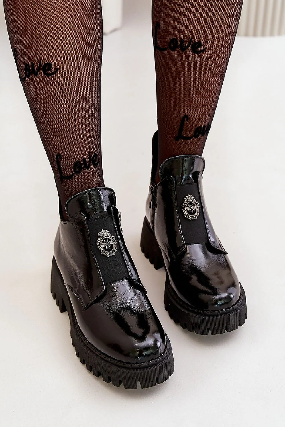 Bottines pour femmes en cuir verni noir talon massif plateforme crantée fermeture élastique métal blason semelle épaisse tige haute cheville