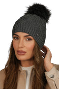 Bonnet tricoté pour femme en laine gris anthracite avec pompon en fausse fourrure noir, coupe ajustée et broche métallique, style élégant et chaleureux pour l'hiver