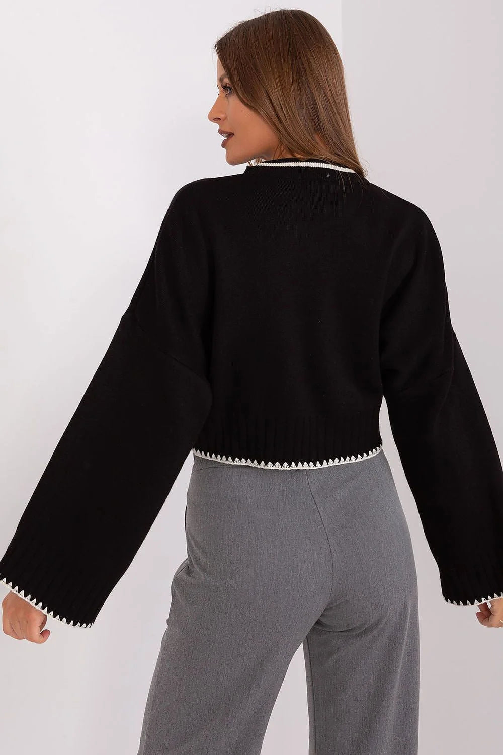 ensemble féminin pull oversize côtelée col rond manches évasées pantalon taille haute poches latérales fermeture bouton finitions contrastées noir blanc