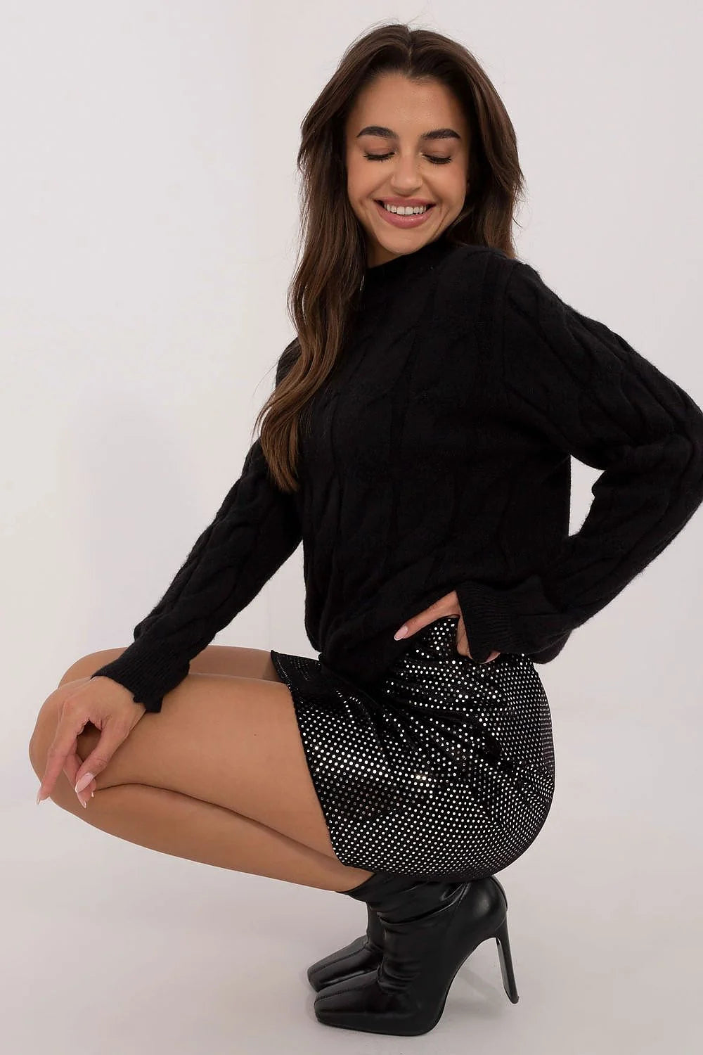 Pull torsadé en laine côtelé noir manches longues col roulé associé à jupe noire à pois argentés polyester femme