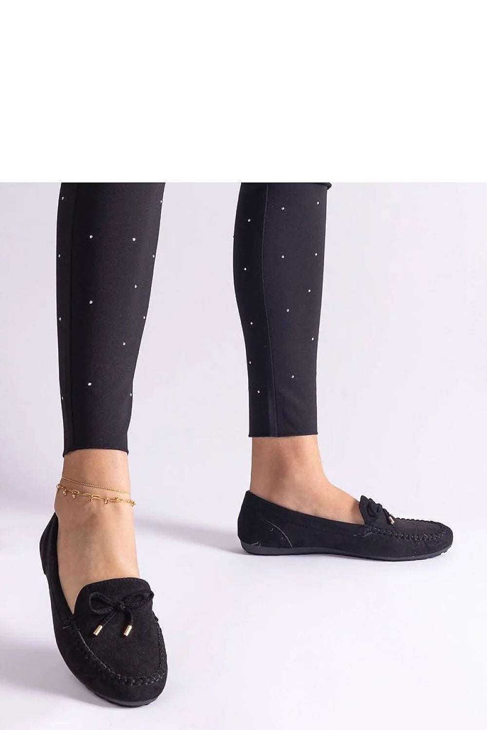 Tenue élégante pour femme pantalon slim ajusté et mocassins noirs en cuir avec détails métalliques et motifs strass