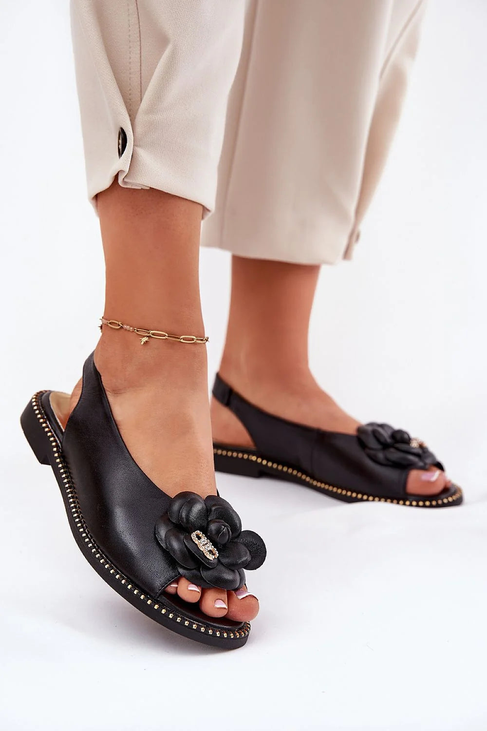 Sandales élégantes pour femmes en cuir noir, slingback, fleur décorative, semelle cloutée dorée, talon plat, style chic et confortable