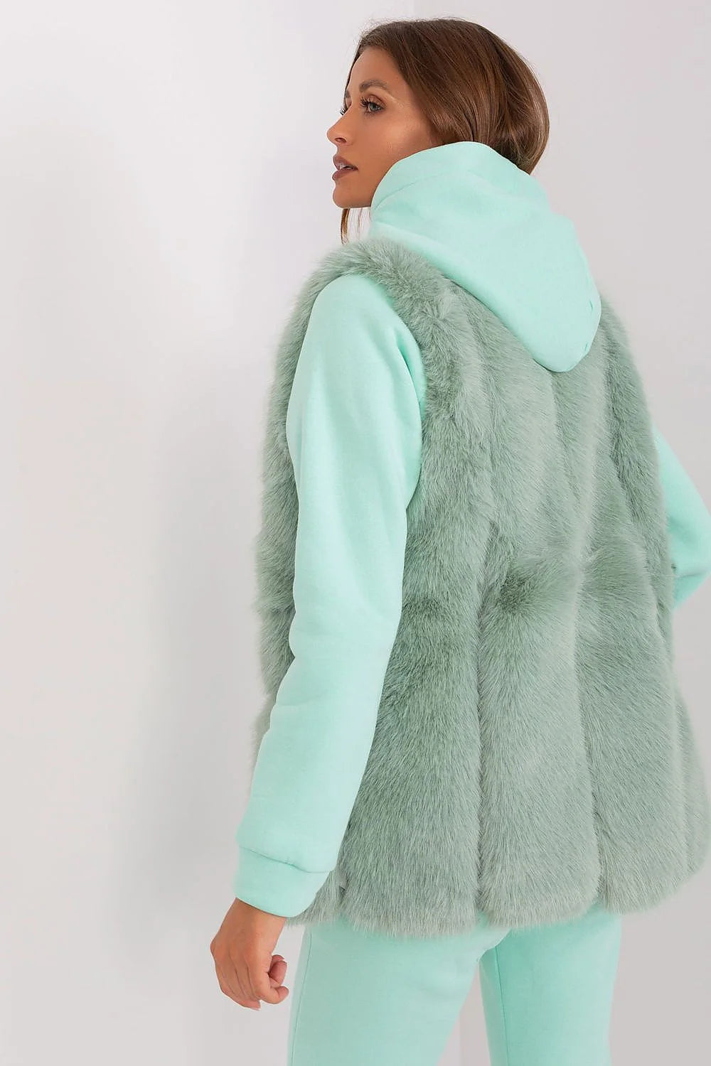 Gilet en fourrure假faux pour femme en vert menthe doux, style casual-chic, sans boutons, texture plush, porté sur un hood et joggers