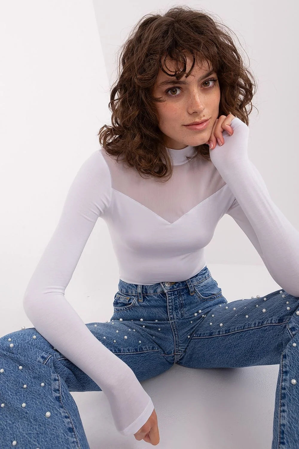 Chemisier transparent en viscose blanche avec haut de buste en maille, associé à un pantalon en denim bleu orné de perles, ensemble élégant pour femme