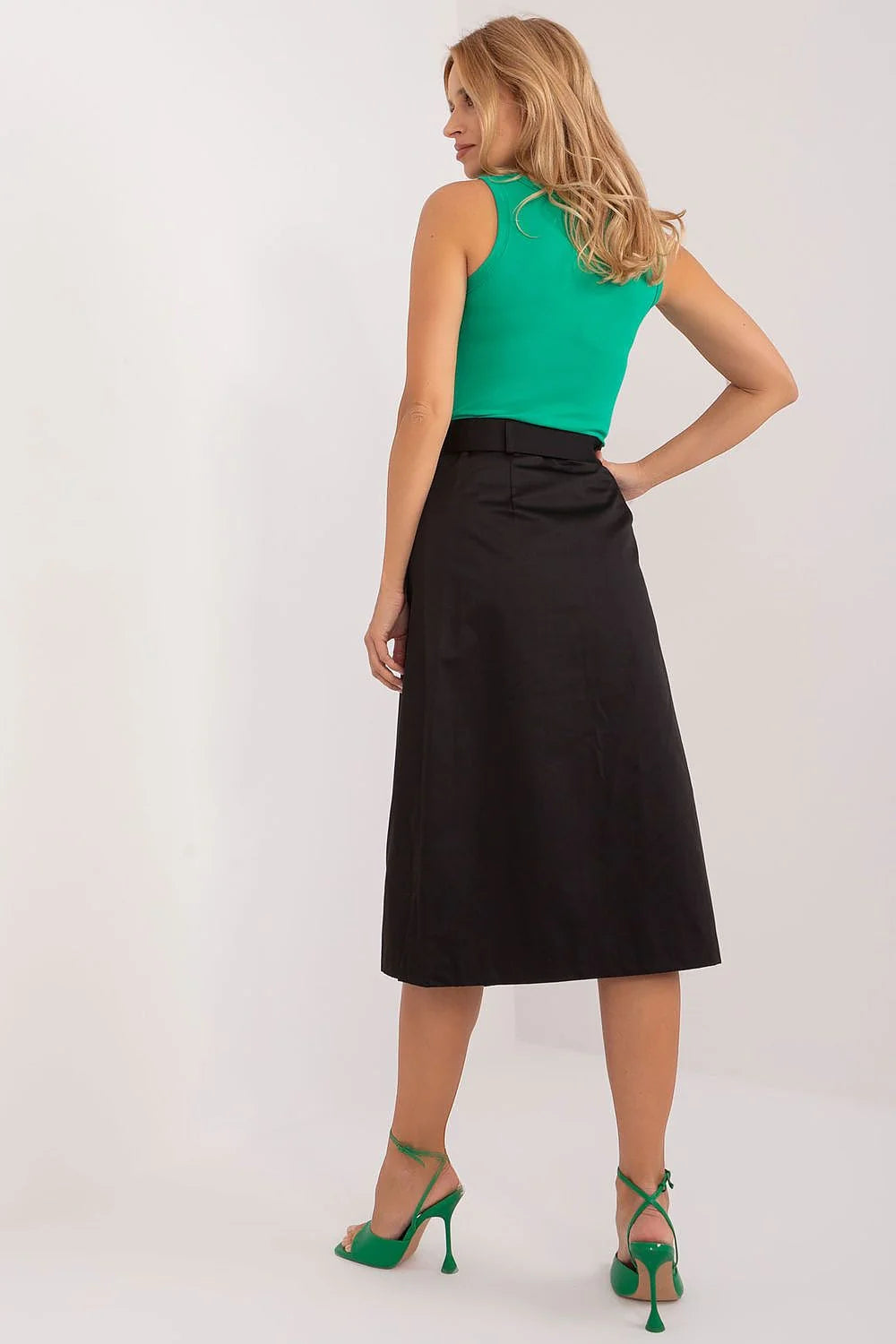 Ensemble élégant et moderne pour femme composé d'un haut vert vif, d'une jupe asymétrique noire et de sandales à talons vert