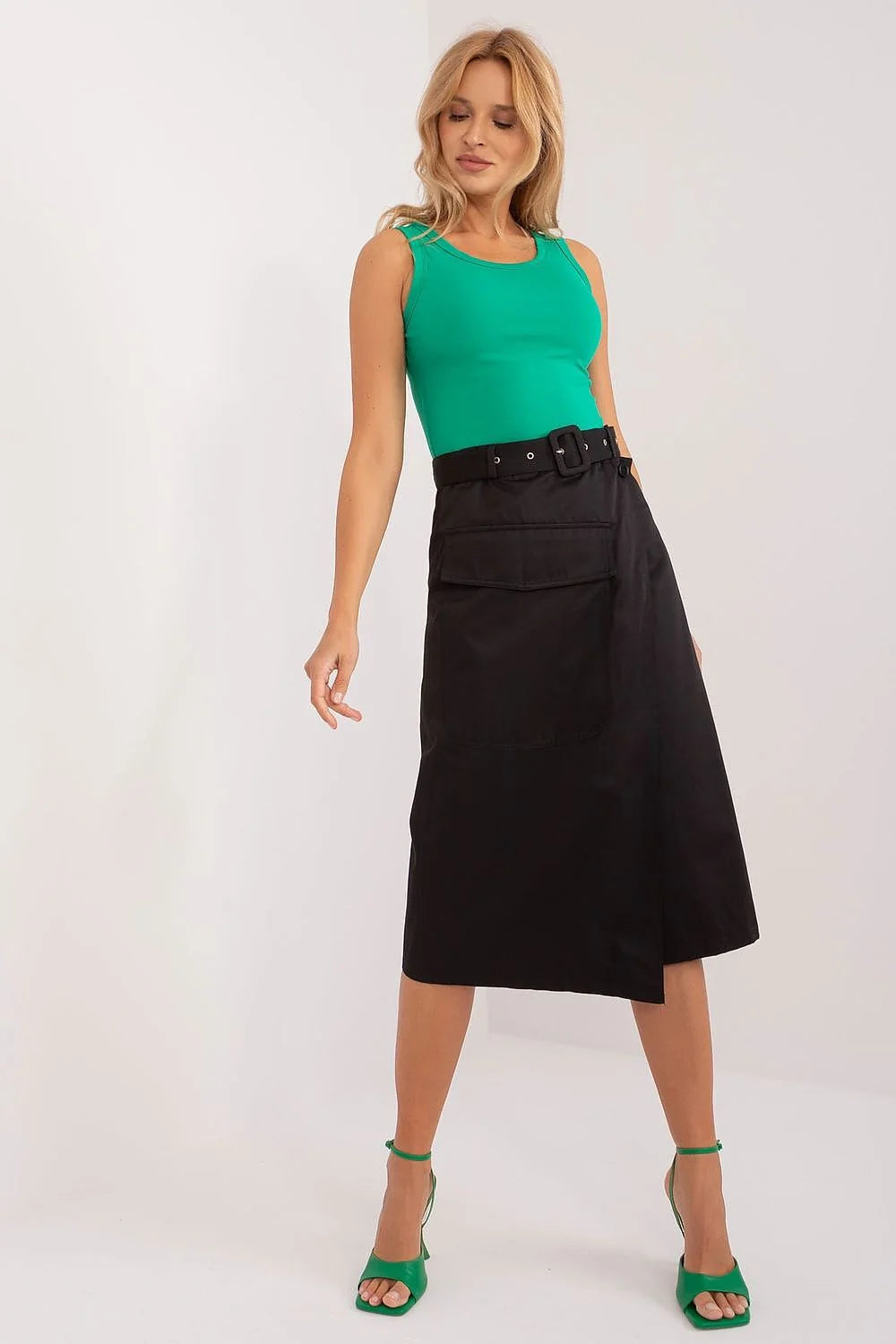 Ensemble élégant et moderne pour femme composé d'un haut vert vif, d'une jupe asymétrique noire et de sandales à talons vert
