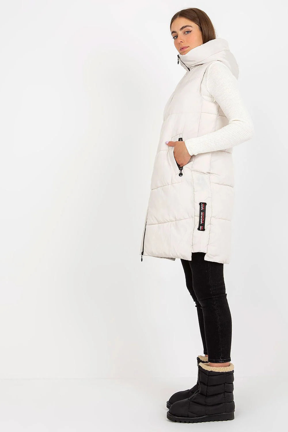Gilet doudoune pour femme en polyester matelassé couleur taupe, coupe longue, sans manches, capuche ajustable et poches latérales