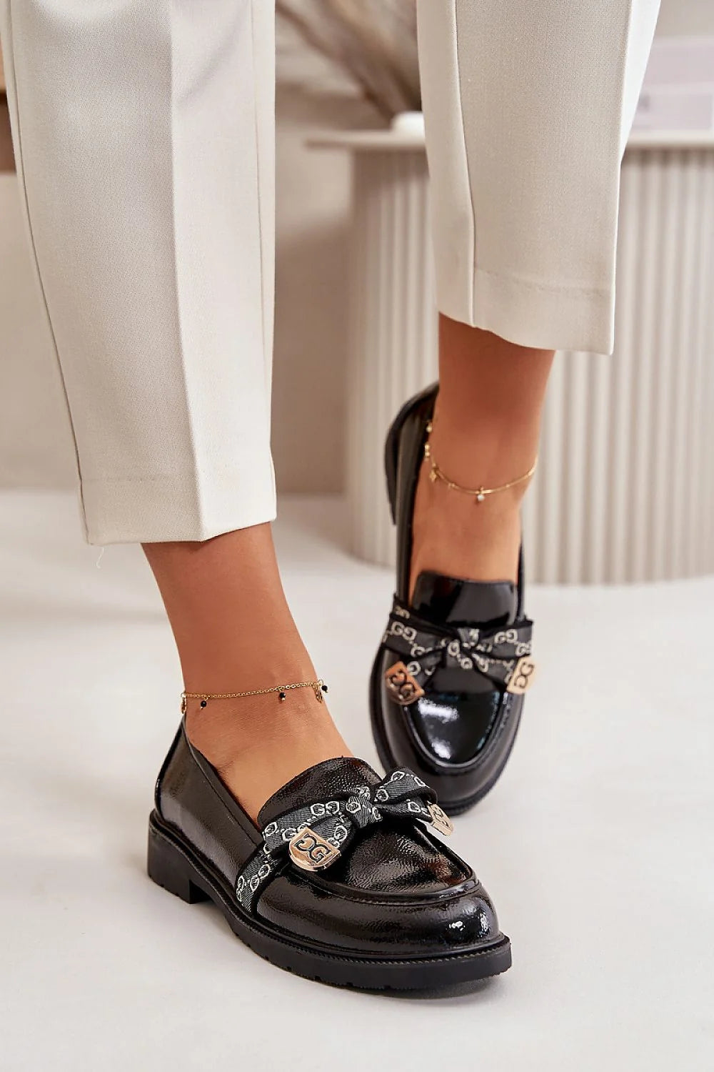 mocassins femme cuir verni noir silhouette basse bout arrondi semelle plateforme crantée talon plat noeud bandeau monogramme plaques métalliques dorées