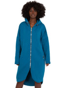 Robe-manteau longue à capuche pour femmes en bleu pétrole, matériau doux, coupe ample, fermeture éclair argentée, poches latérales, style moderne et confortable