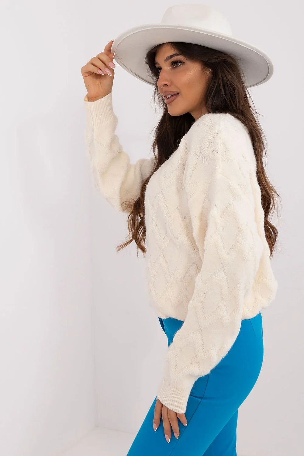 Pull crème motif losange épaules tombantes manches bouffantes pantalon bleu ajusté chapeau large bord blanc cassé tenue féminine mode élégante moderne