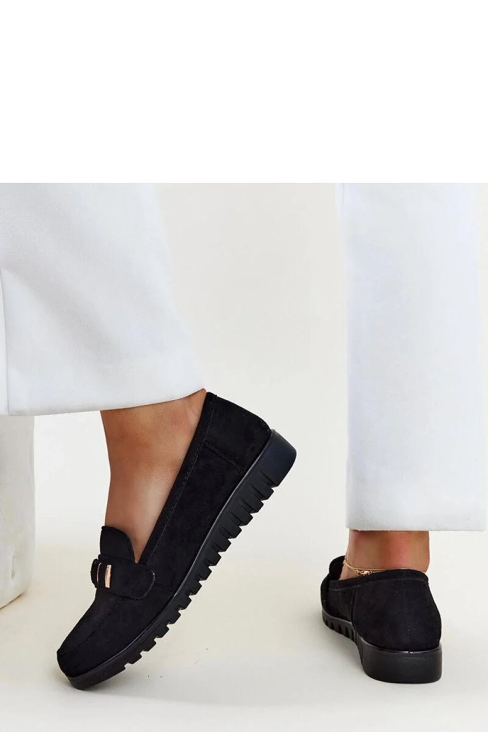 Mocassins femmes style intemporel couleur noire matériau doux détails métal doré confortable porté avec pantalon blanc accessoires dorés élégance mode