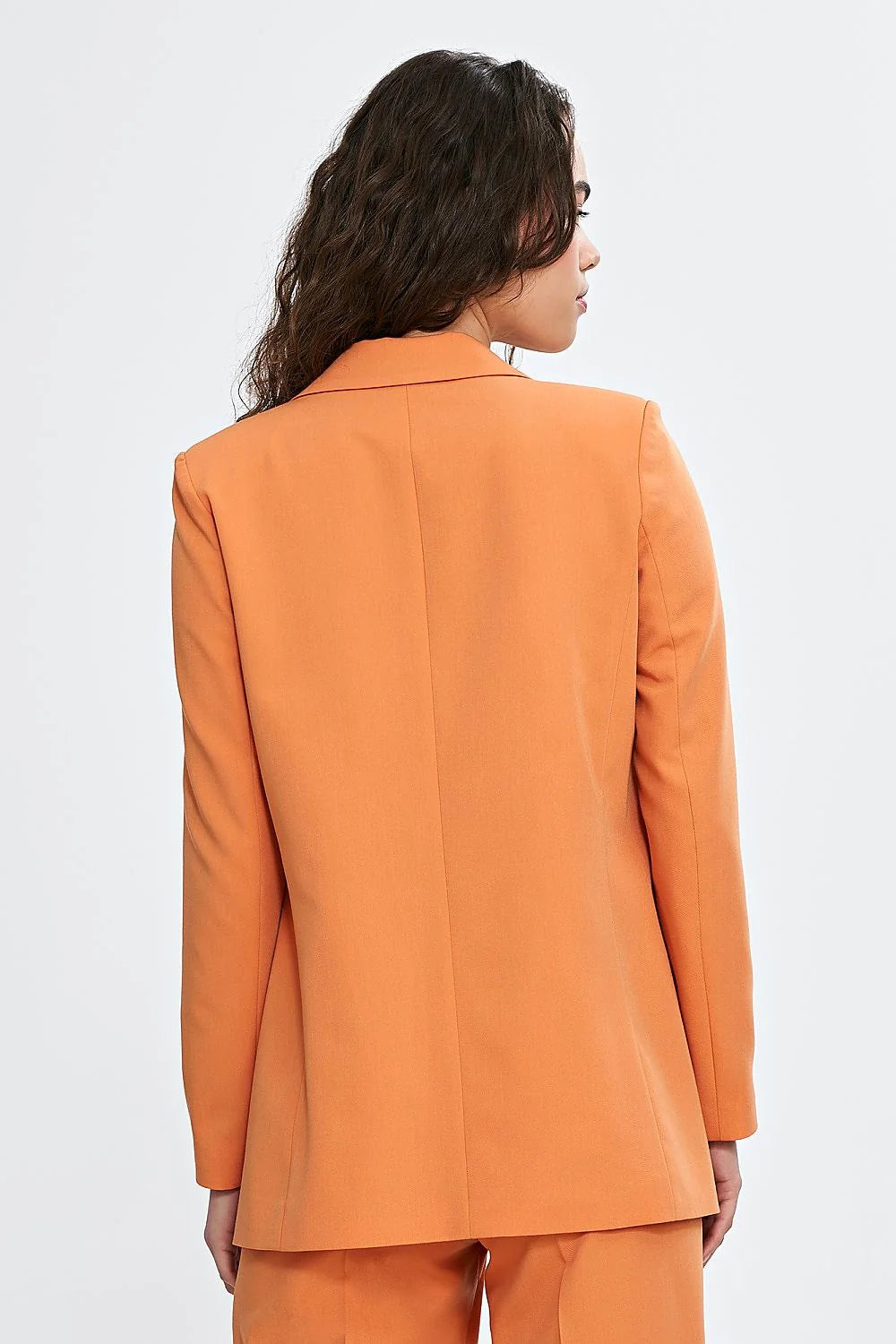 Tailleur élégant pour femme en orange vibrant, veste et pantalon, coupe classique, manches longues, épaules définies, occasion professionnelle