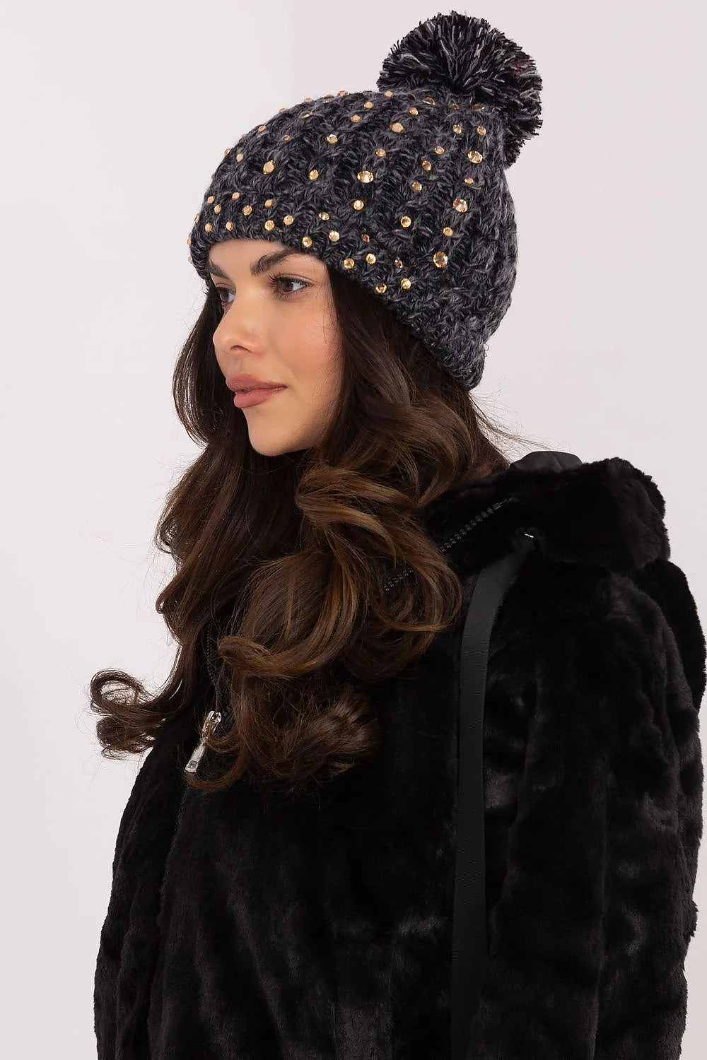 Bonnet de mode élégant pour femmes en matière tricotée épaisse couleur gris foncé avec strass dorés et pompon moelleux ajustement élastique finitions précises style chic et contemporain pour hiver