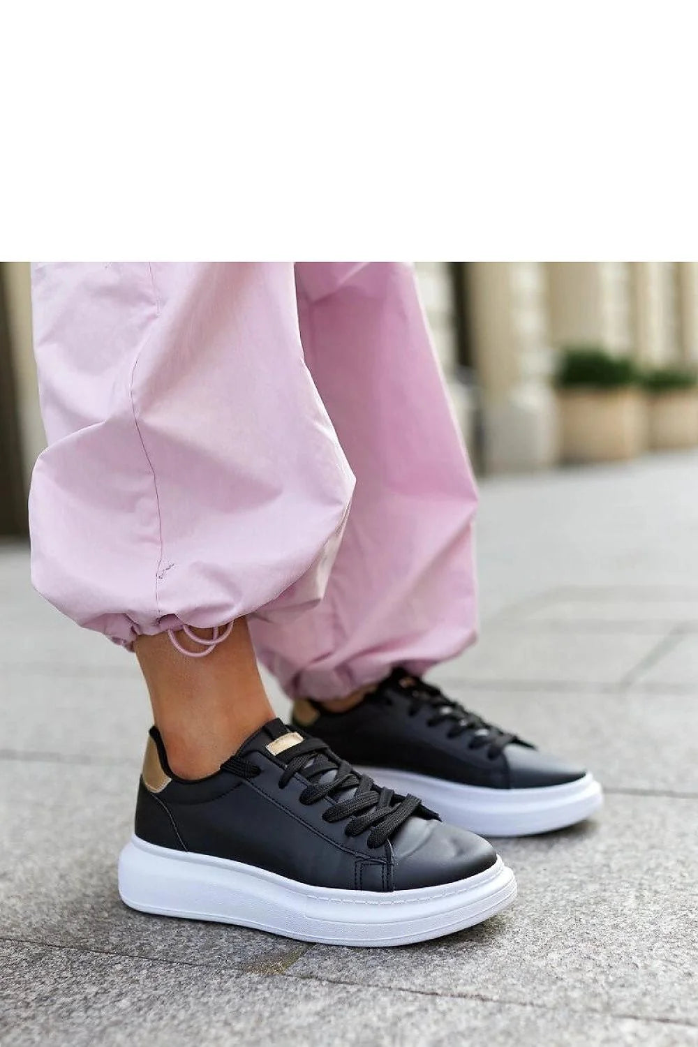 Baskets mode femmes cuir noir semelle épaisse blanche design minimaliste style sophistiqué confortable lacets noirs détails métalliques dorés