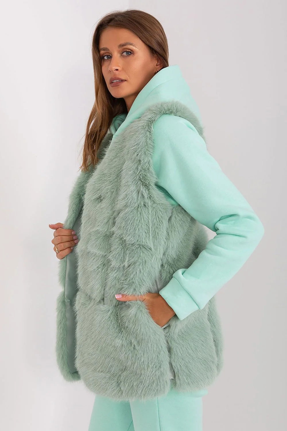 Gilet en fourrure假faux pour femme en vert menthe doux, style casual-chic, sans boutons, texture plush, porté sur un hood et joggers