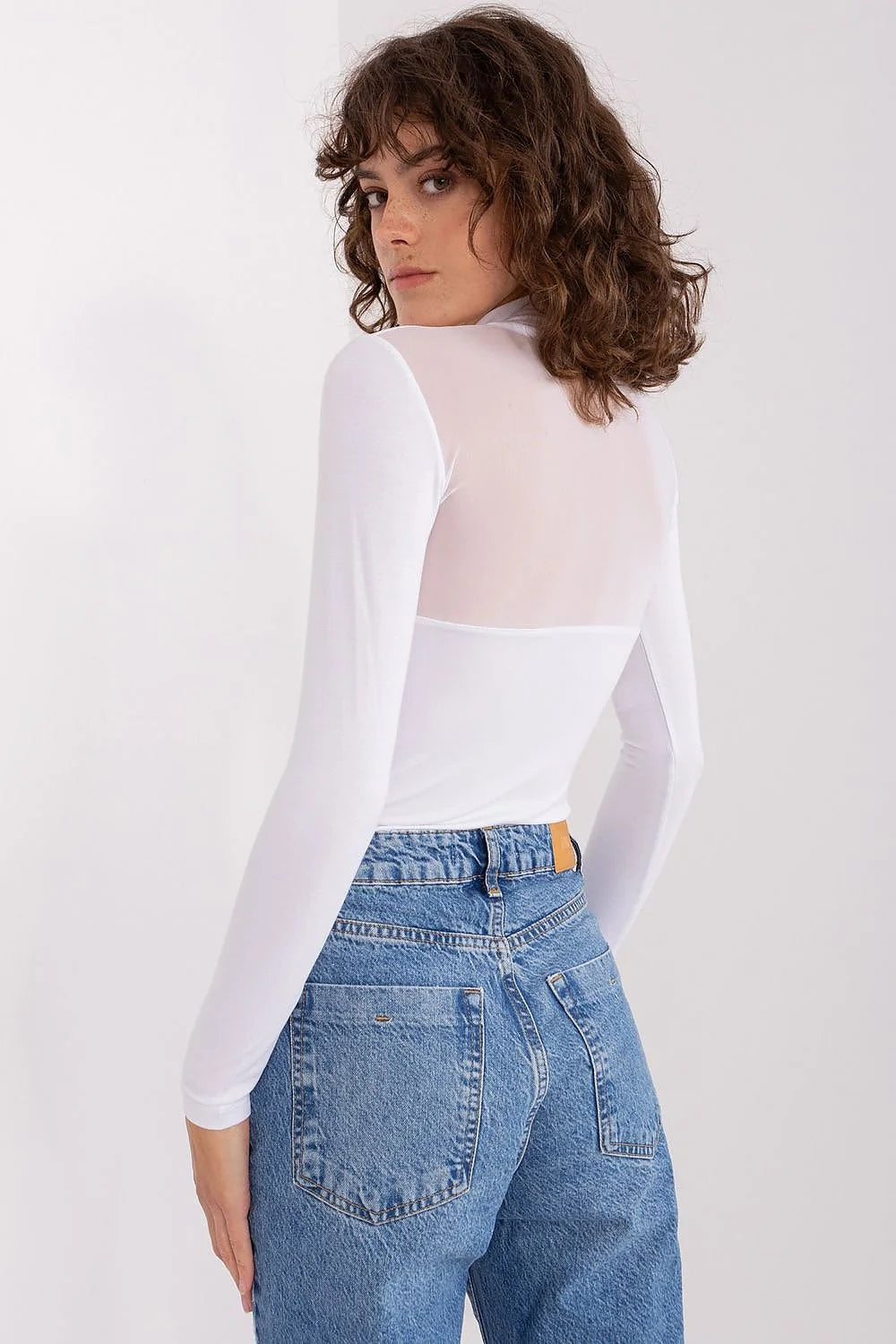 Chemisier transparent en viscose blanche avec haut de buste en maille, associé à un pantalon en denim bleu orné de perles, ensemble élégant pour femme