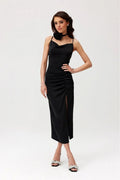 Robe de cocktail élégante noire longueur midi dos nu bretelles fines tissu satiné fente jambe fleur accessoire femme