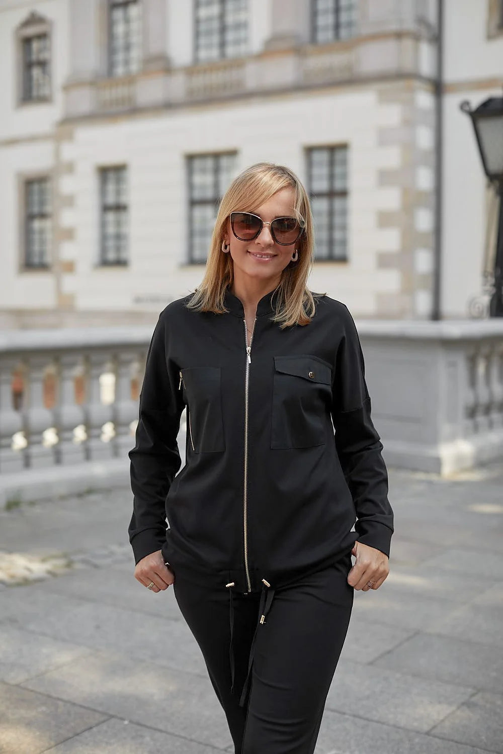 ensemble féminin bomber joggers noir zippé brillant polyester légèrement ajustée confortable urbain chic fuselé poches rabats élastiques cordon embouts dorés