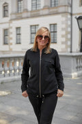 ensemble féminin bomber joggers noir zippé brillant polyester légèrement ajustée confortable urbain chic fuselé poches rabats élastiques cordon embouts dorés