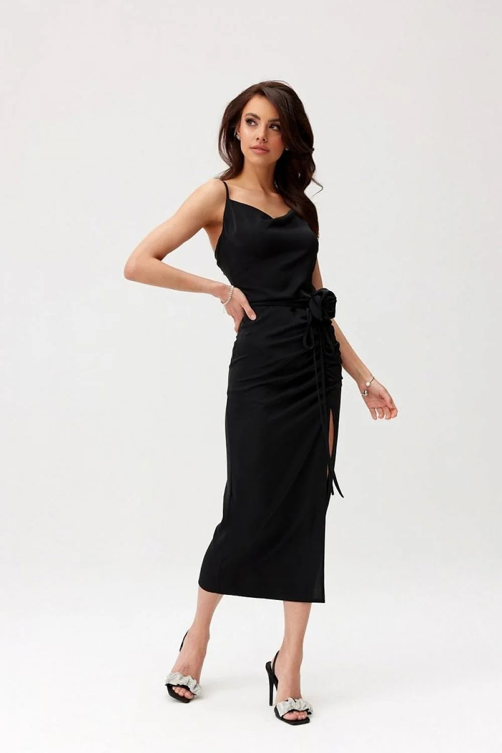 Robe de cocktail élégante noire longueur midi dos nu bretelles fines tissu satiné fente jambe fleur accessoire femme