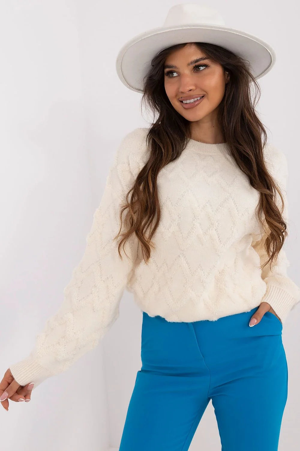 Pull crème motif losange épaules tombantes manches bouffantes pantalon bleu ajusté chapeau large bord blanc cassé tenue féminine mode élégante moderne