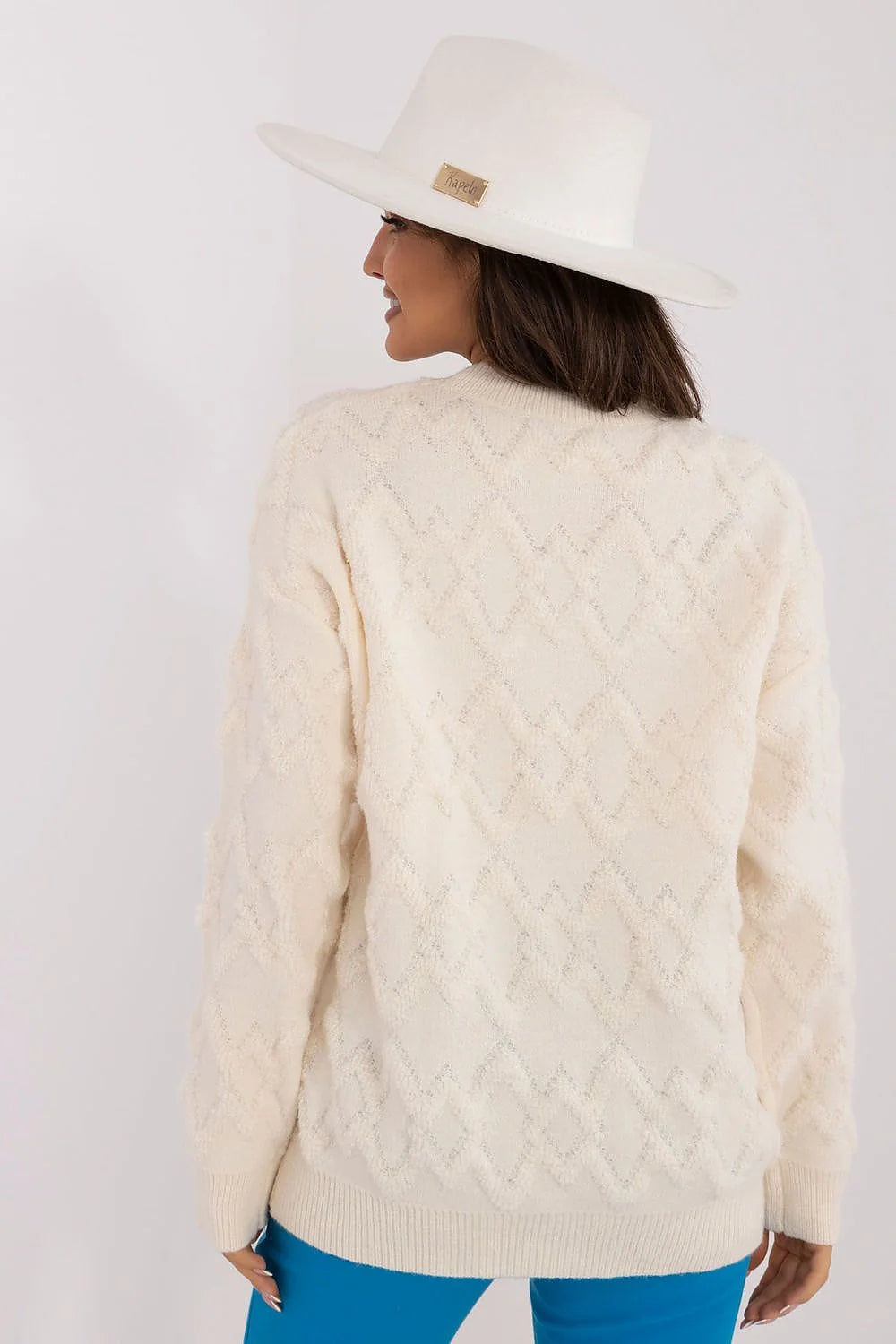 Pull crème motif losange épaules tombantes manches bouffantes pantalon bleu ajusté chapeau large bord blanc cassé tenue féminine mode élégante moderne