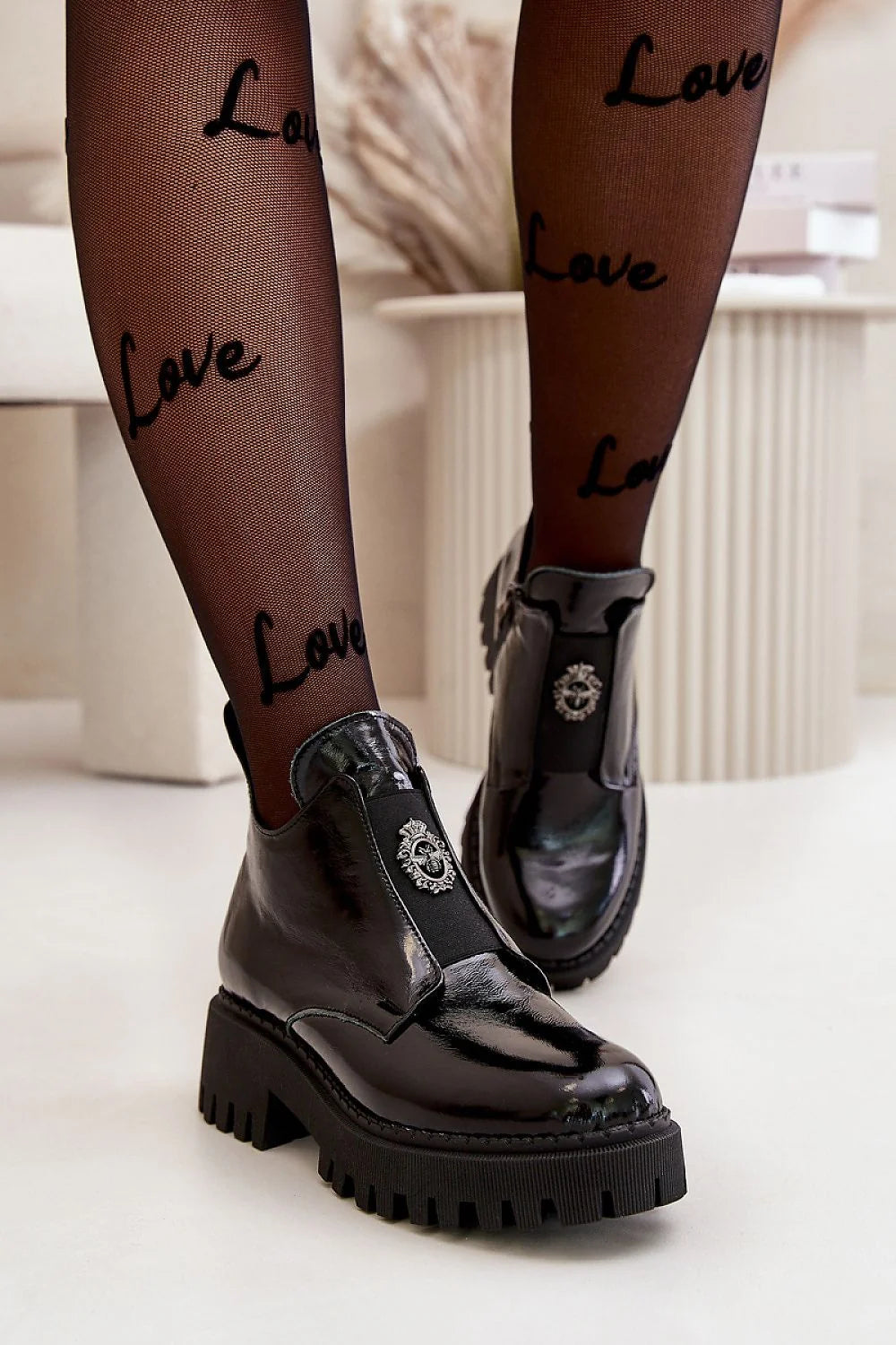 Bottines pour femmes en cuir verni noir talon massif plateforme crantée fermeture élastique métal blason semelle épaisse tige haute cheville