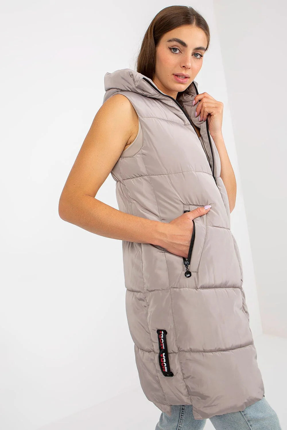 Gilet doudoune pour femme en polyester matelassé couleur taupe, coupe longue, sans manches, capuche ajustable et poches latérales