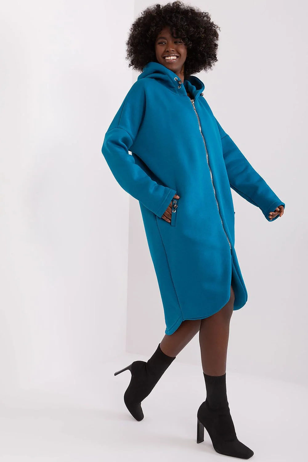 Robe-manteau longue à capuche pour femmes en bleu pétrole, matériau doux, coupe ample, fermeture éclair argentée, poches latérales, style moderne et confortable